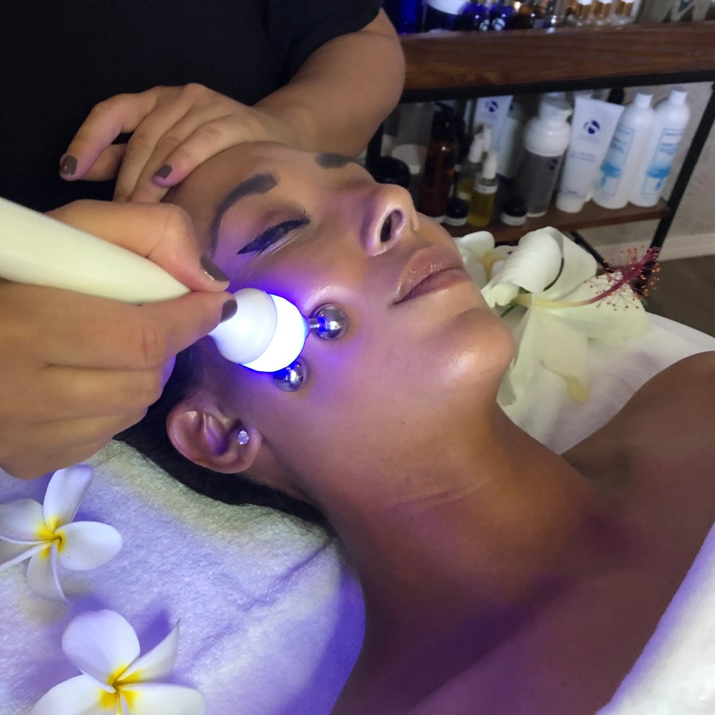 LED light facial in progress with a plumeria flower resting beside the client