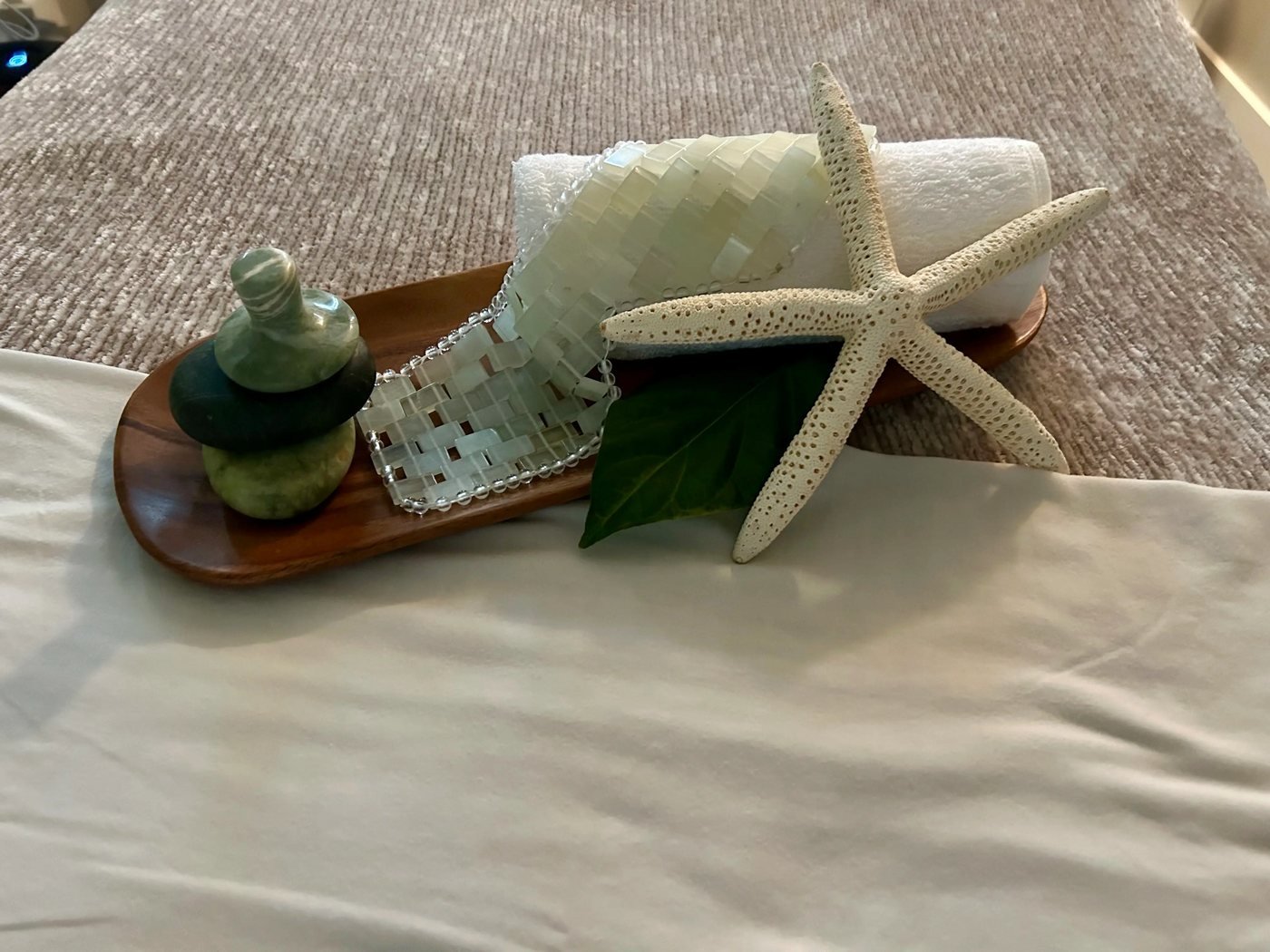 Rolled towel, starfish, and essential oils arranged on a spa tray